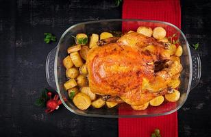 Baked turkey or chicken. The Christmas table is served with a turkey, decorated with bright tinsel. Fried chicken, table. Christmas dinner.  Top view, above