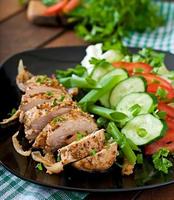Baked chicken breast and fresh vegetables on the plate on a wooden background photo