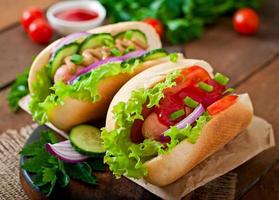 Hotdog with ketchup, mustard, lettuce and vegetables on wooden table