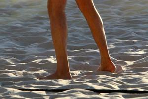 A man walks barefoot on the sand by the sea photo