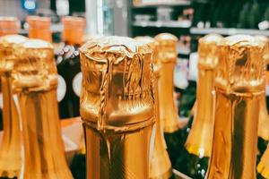 Lots of champagne bottles in store. Sale of alcoholic beverages before holiday. Close up of bottlenecks. photo