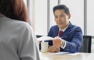 Senior executive businessman with serious face giving paper to young female at the office. Recruitment concept, termination from economic crisis concept. photo