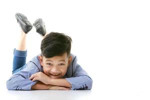 A 10-year-old Asian boy in a casual jacket is lying on the floor and smiling happily in a good mood looking at the camera. Positive concepts for children and young men's lifestyles. photo