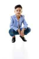 A 10-year-old Asian boy in a casual jacket is sitting smart and happy looking at the camera against a white isolate background.