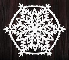 snowflake carved from paper on dark brown plank photo