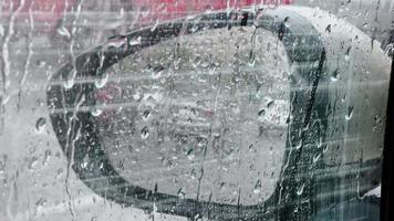 Heavy rain, drops falling on car window through which side mirror is visible. video