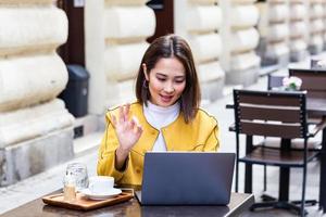 hermosa joven estudiante asiática que usa una computadora portátil mientras está sentada en una cafetería vintage. joven y bella chica que usa una computadora portátil personal para buscar información en Internet foto