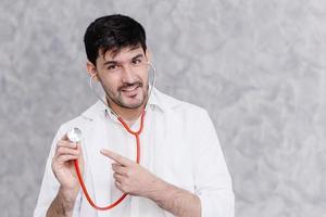 Handsome doctor hand pointing at stethoscope for call for healthy check or remind to medication treatment concept photo