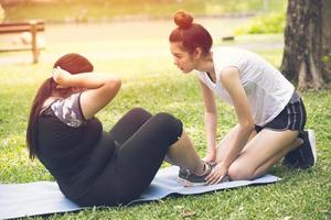 entrenador personal entrenador adolescente ayuda a entrenar a una amiga gorda para hacer ejercicio de dieta saludable al aire libre en el parque foto