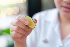 mano de niña exprimiendo un poco de jugo de limón de lima ácido natural de alta nutrición bueno para una bebida saludable foto