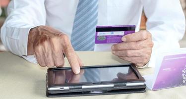 A business man touches his hand on a digital tablet to do credit card shopping. photo