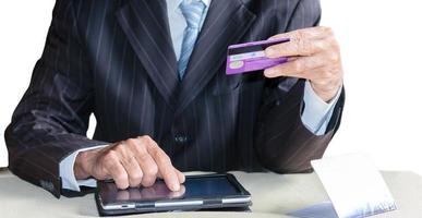 Close-up of a male businessman using a credit card to make purchases on a digital tablet. photo