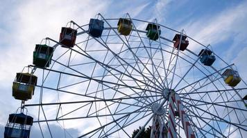 Colorful ferris wheels in the amusement park on a background of blue sky with clouds. Toned image. Bottom view photo