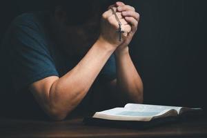 Man reading holy bible book and folding hands pray to God. photo