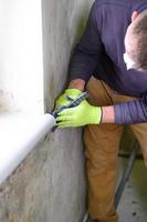 Fungus and mold is a manifestation of excess moisture in the room, a man with a spatula removes fungus and mold from the wall. photo