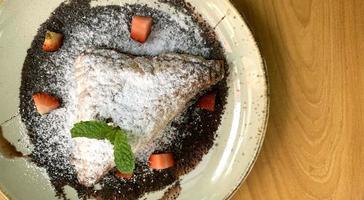 empanadillas de manzana espolvoreadas con azúcar glas con trocitos de fresa y salsa de chocolate foto