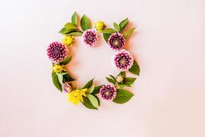 a round frame of autumn flowers on a white background. bright dahlias and green leaves. autumn floral concept. flower wreath. photo