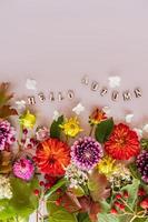vertical flat view of cut autumn flowers and twigs with red viburnum berry. bright autumn border, postcard. wooden letters with the text-hello autumn. photo