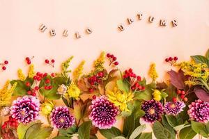 festive autumn composition of cut garden flowers, leaves and berries. beige background with the inscription -hello autumn. floral border. photo