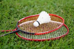 volante de bádminton y raqueta en el suelo de hierba. concepto, deporte con equipo, entrenamiento. deporte recreativo que se puede jugar por diversión o ejercicio y competencia en equipo o individual. foto