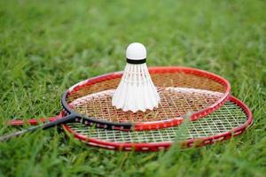 volante de bádminton y raqueta en el suelo de hierba. concepto, deporte con equipo, entrenamiento. deporte recreativo que se puede jugar por diversión o ejercicio y competencia en equipo o individual. foto