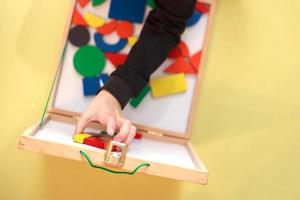 el niño juega juegos educativos magnéticos de madera. vista desde arriba. niño juega con un constructor foto