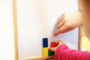el niño juega un juego educativo magnético de madera. niña juega con un juguete sobre un fondo blanco foto