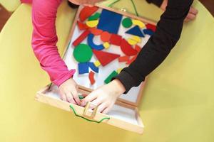 children play wooden magnetic educational games together. view from above. kids play with a constructor photo