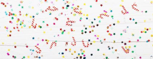 Christmas background with candy canes and multicolored sequins on blue wooden background photo