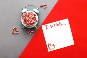 Christmas background with candy canes on alarm clock on gray and red background photo