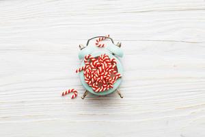 Christmas background with candy canes on alarm clock on wooden background photo