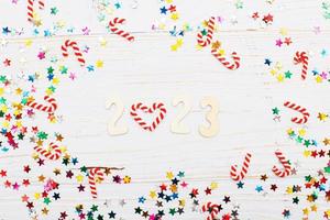 fondo de navidad con bastones de caramelo y lentejuelas multicolores sobre fondo de madera azul número 2023 foto