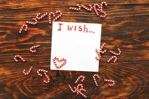 notebook with wish list on vintage wooden table with candy canes. christmas planning concept. photo