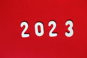 inscripción 2023 con números de madera sobre fondo rojo .concepto festivo foto