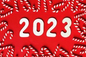 Christmas composition with candy canes and number 2023 on a red background. Copy space for text photo