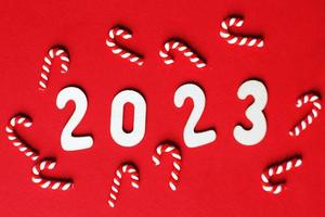 Christmas composition with candy canes and number 2023 on a red background. Copy space for text photo