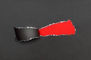 curl of torn black paper on red background. advertising and sale concept. copy space photo