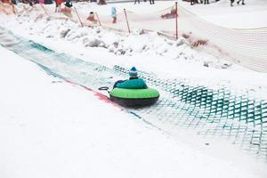 Child having fun on snow tube. Boy is riding a tubing. Winter entertainment. kid sliding downhill on tube photo