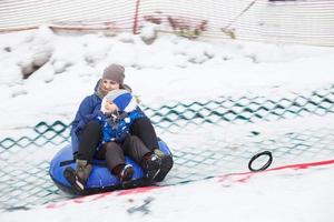 Family having fun on snow tube. mother with kid is riding a tubing. people sliding downhill on tube photo