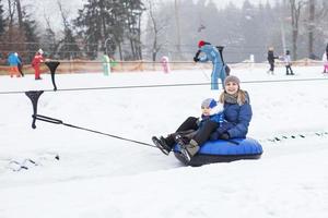 Family having fun on snow tube. mother with kid is riding a tubing. people sliding downhill on tube. ride a lift photo