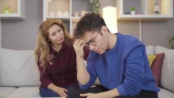 Mother supports her sad son. Sad mother and son sitting at home. video