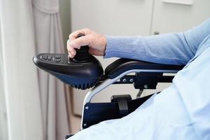 Asian elderly woman disability patient sitting on electric wheelchair in park, medical concept. photo