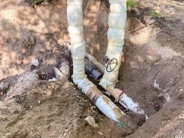 laying of underground communications for residential buildings. plumbing pipes in black with a huge white valve to regulate the flow of water photo