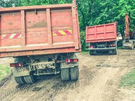 a truck with a body for transporting heavy things. heavy-duty vehicle sticker on the back of the body. the car drives on a muddy road and leaves tire marks photo