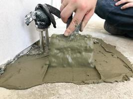 Builder hands with a metal spatula plaster the wall, pours the screed with plaster, tile glue, cement for the repair of the apartment, building a house, leveling the walls photo