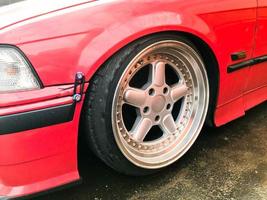Beautiful big racing wheels of a sports red car with a very low ground clearance on cast shiny expensive alloy wheels in the style of Stans. Tuning cars photo