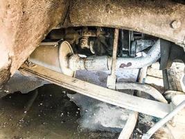 Old rusty worn muffler of a truck, car. Car suspension repair. Replacing wheel photo