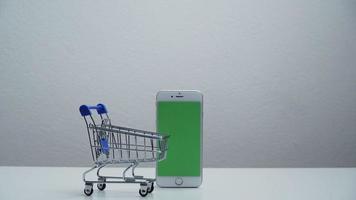 Stoppen Sie die Bewegung eines Einkaufswagens, der sich auf dem grünen Bildschirm des Smartphones bewegt. video