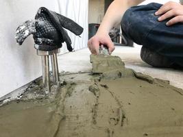Builder hands with a metal spatula plaster the wall, pours the screed with plaster, tile glue, cement for the repair of the apartment, building a house, leveling the walls and pouring photo