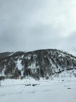 Beautiful mountain cold winter resort landscapes with high mountain peaks mist and snow covered rocks for snowboarding and skiing against a blue sky photo